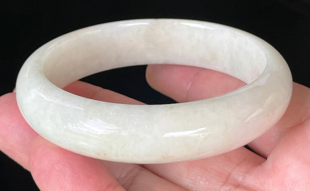 Close-up of fine crystalline texture and warm honey hues on icy milky white jadeite bangle