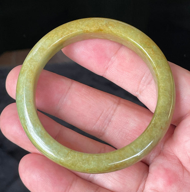 Close-up of fine crystalline texture and earthy brown undertones on moss and apple green jadeite bangle