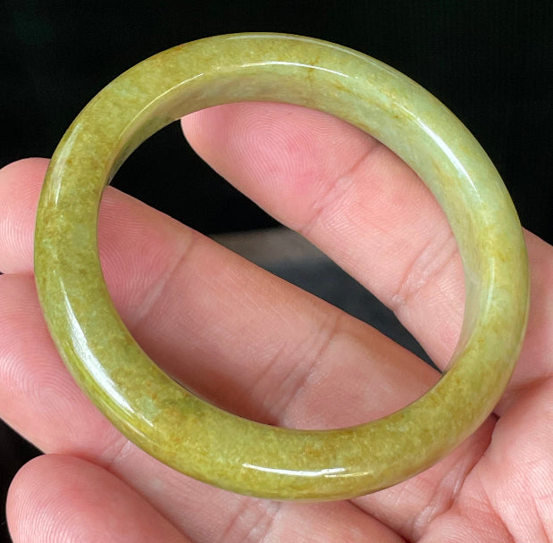 Close-up of fine crystalline texture and earthy brown undertones on moss and apple green jadeite bangle