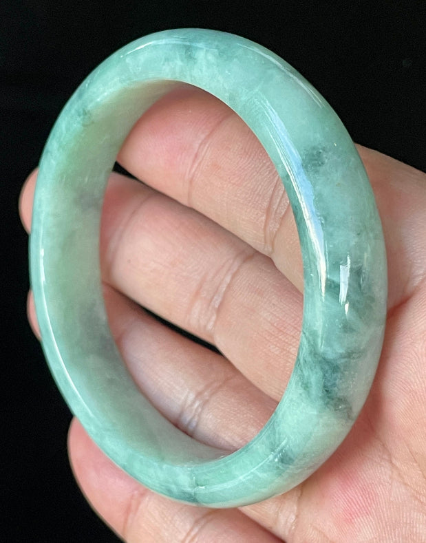 Close-up of fine crystalline texture and beautiful moss in the snow pattern on icy imperial green and white jadeite bangle