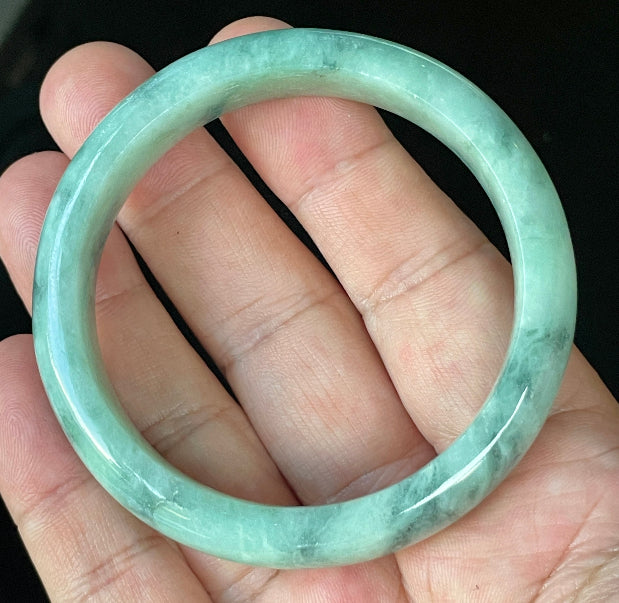 Close-up of fine crystalline texture and beautiful moss in the snow pattern on icy imperial green and white jadeite bangle
