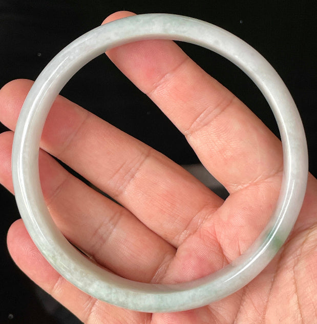 Close-up of fine crystalline texture and striking imperial green accent on icy greyish white jadeite bangle
