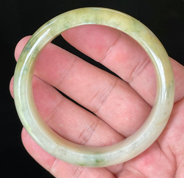 Close-up of fine crystalline texture and vivid green hues on icy yellow and white jadeite bangle