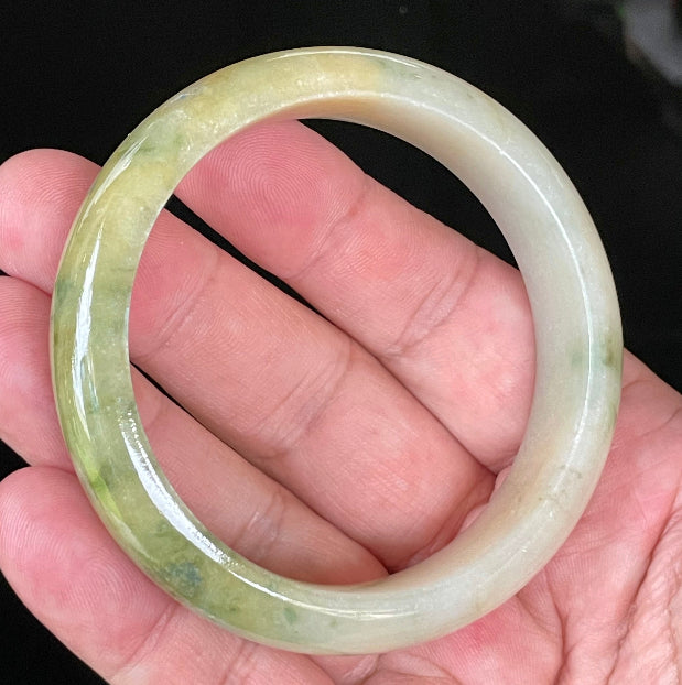 Close-up of fine crystalline texture and vivid green hues on icy yellow and white jadeite bangle