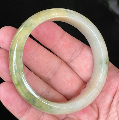 Close-up of fine crystalline texture and vivid green hues on icy yellow and white jadeite bangle