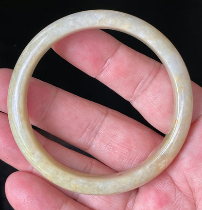 Close-up of fine crystalline texture and warm honey orange hues on icy yellow jadeite bangle
