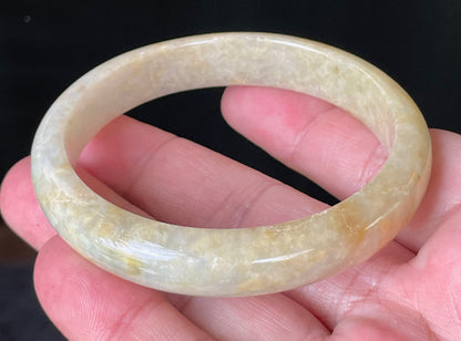 Close-up of fine crystalline texture and warm honey orange hues on icy yellow jadeite bangle