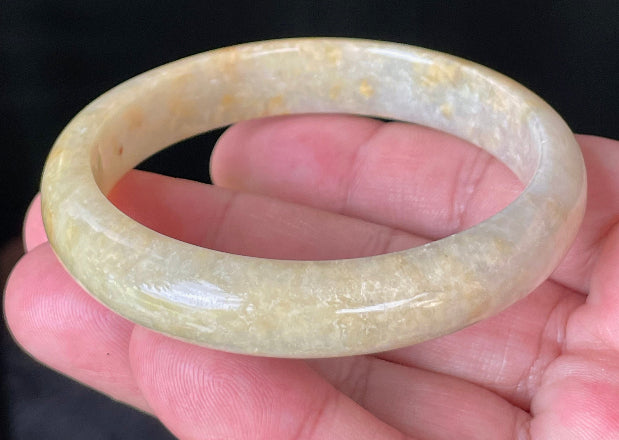 Close-up of fine crystalline texture and warm honey orange hues on icy yellow jadeite bangle