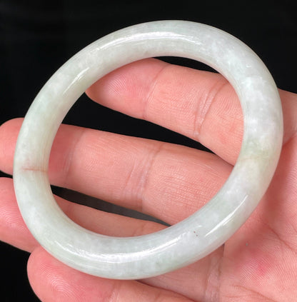 Close-up of fine crystalline texture and a natural orange line on icy milky white and apple green jadeite bangle