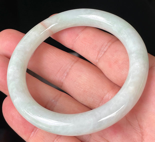 Close-up of fine crystalline texture and a natural orange line on icy milky white and apple green jadeite bangle