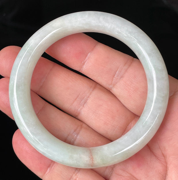 Close-up of fine crystalline texture and a natural orange line on icy milky white and apple green jadeite bangle