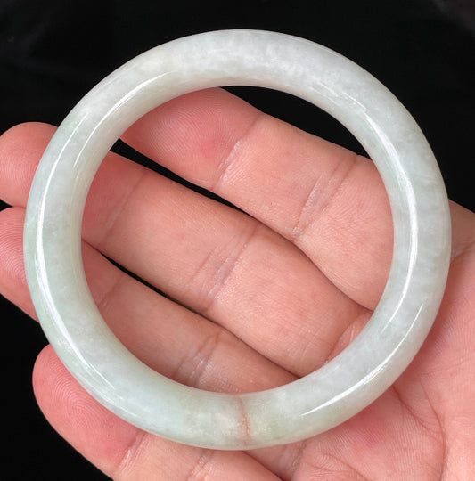 Close-up of fine crystalline texture and a natural orange line on icy milky white and apple green jadeite bangle