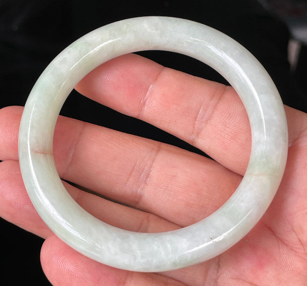 Close-up of fine crystalline texture and a natural orange line on icy milky white and apple green jadeite bangle