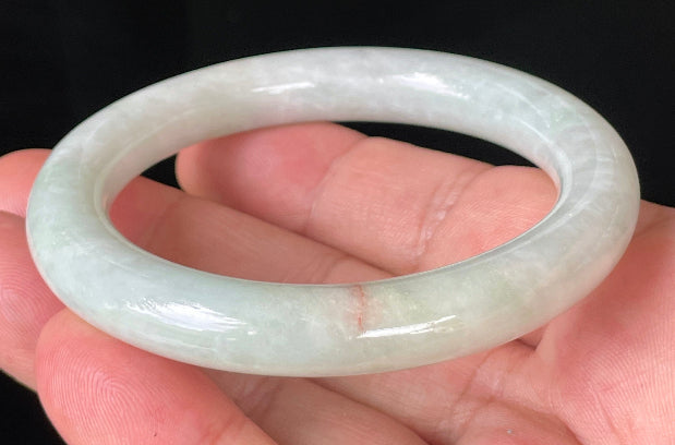 Close-up of fine crystalline texture and a natural orange line on icy milky white and apple green jadeite bangle