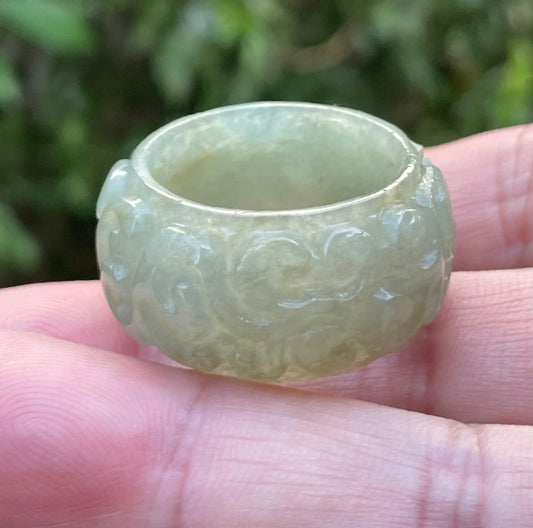 Close-up of flowing curves and continuous hand-carved round swirl motif on an icy apple green Burmese jade ring