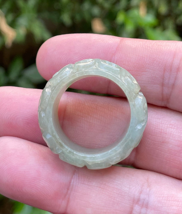 Close-up of flowing curves and continuous hand-carved round swirl motif on an icy apple green Burmese jade ring