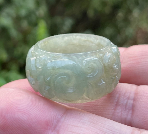 Close-up of flowing curves and continuous hand-carved round swirl motif on an icy apple green Burmese jade ring