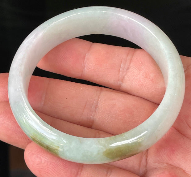 Close-up of fine crystalline texture and gentle lavender hues on icy milky white and green jadeite bangle