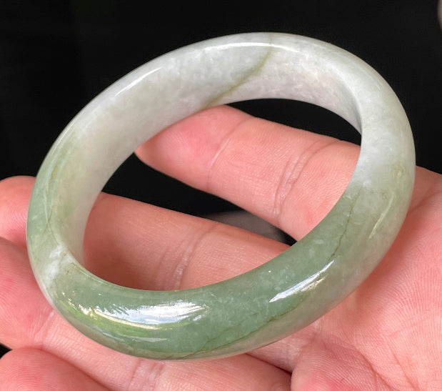Close-up of fine crystalline texture and apple green hues on icy milky white jadeite bangle