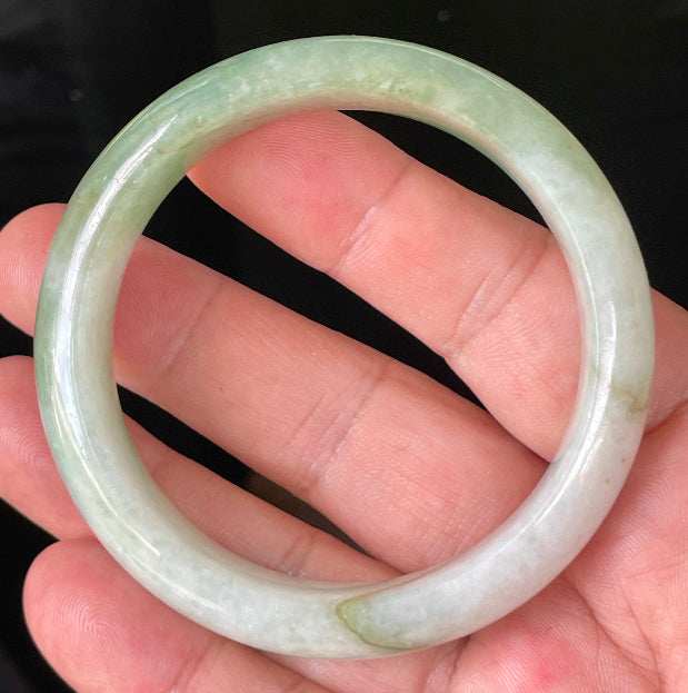 Close-up of fine crystalline texture and apple green hues on icy milky white jadeite bangle