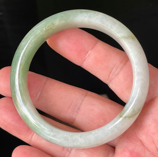 Close-up of fine crystalline texture and apple green hues on icy milky white jadeite bangle