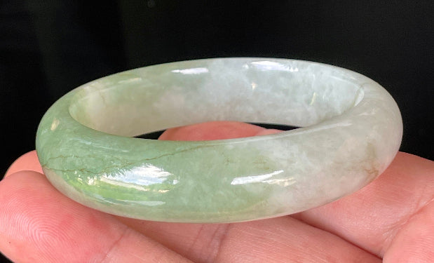 Close-up of fine crystalline texture and apple green hues on icy milky white jadeite bangle