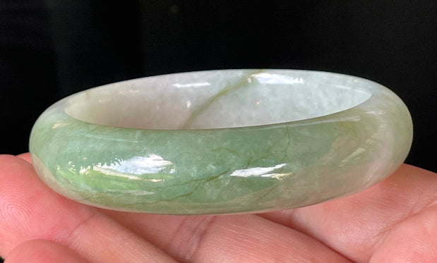 Close-up of fine crystalline texture and apple green hues on icy milky white jadeite bangle