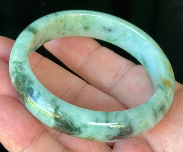 Close-up of fine crystalline texture and honey tones on icy forest green jadeite bangle