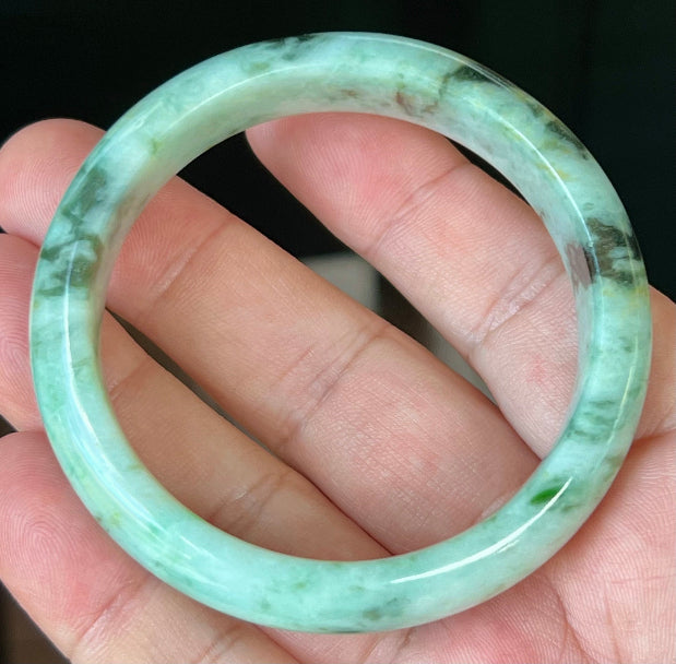 Close-up of fine crystalline texture and honey tones on icy forest green jadeite bangle