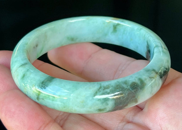 Close-up of fine crystalline texture and honey tones on icy forest green jadeite bangle