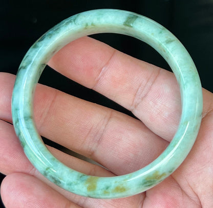 Close-up of fine crystalline texture and honey tones on icy forest green jadeite bangle