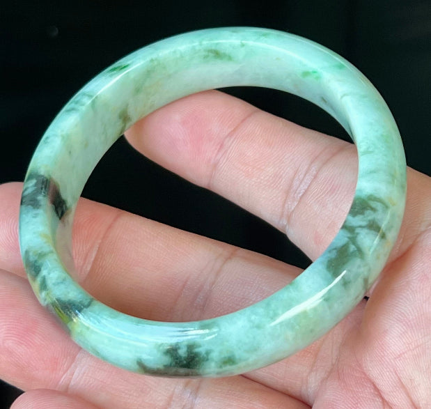 Close-up of fine crystalline texture and honey tones on icy forest green jadeite bangle