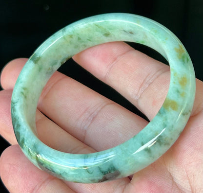 Close-up of fine crystalline texture and honey tones on icy forest green jadeite bangle
