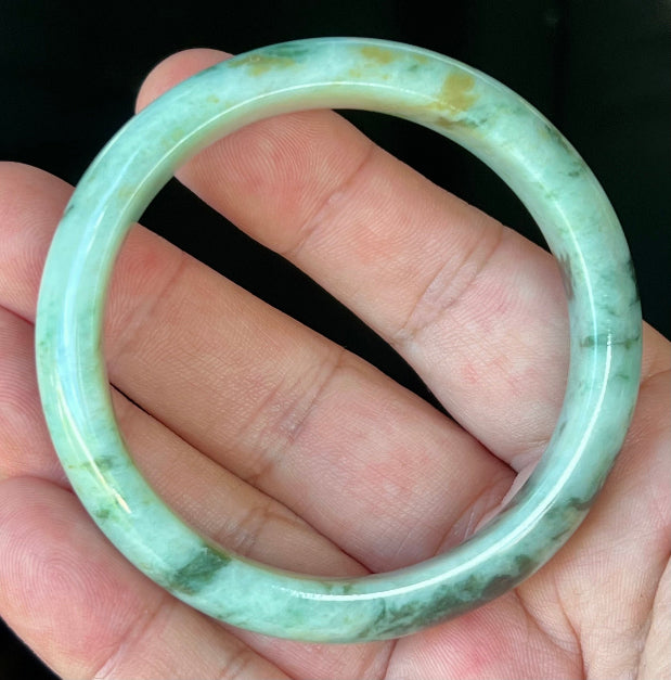 Close-up of fine crystalline texture and honey tones on icy forest green jadeite bangle