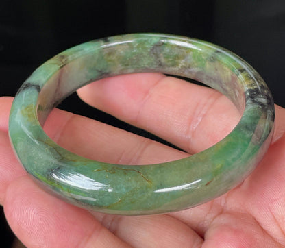 Close-up of fine crystalline texture and deep black patterns on icy imperial green jadeite bangle