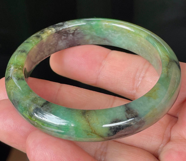 Close-up of fine crystalline texture and deep black patterns on icy imperial green jadeite bangle