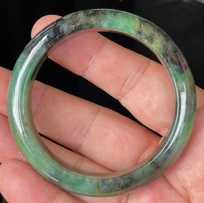 Close-up of fine crystalline texture and deep black patterns on icy imperial green jadeite bangle