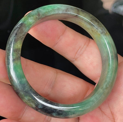 Close-up of fine crystalline texture and deep black patterns on icy imperial green jadeite bangle
