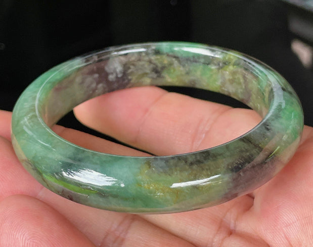 Close-up of fine crystalline texture and deep black patterns on icy imperial green jadeite bangle