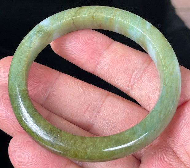 Close-up of fine crystalline texture and subtle bluish tones on icy forest green jadeite bangle