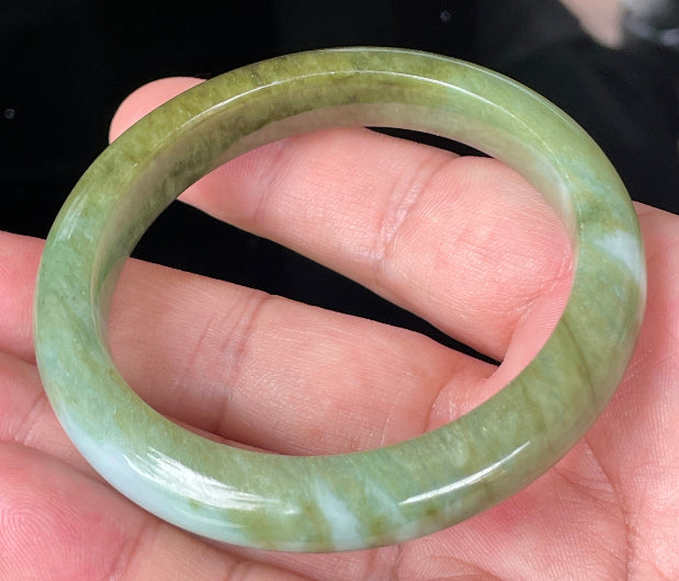 Close-up of fine crystalline texture and subtle bluish tones on icy forest green jadeite bangle
