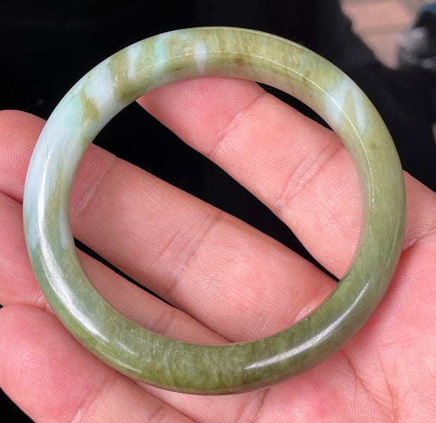 Close-up of fine crystalline texture and subtle bluish tones on icy forest green jadeite bangle