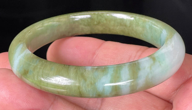 Close-up of fine crystalline texture and subtle bluish tones on icy forest green jadeite bangle