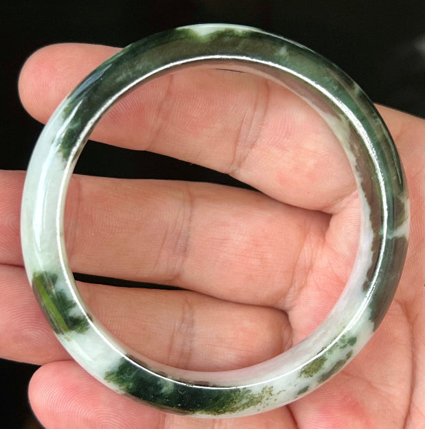 Close-up of fine crystalline texture and lush forest green patterns on icy milky white jadeite bangle