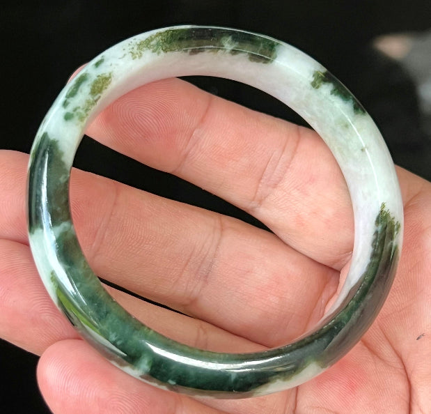 Close-up of fine crystalline texture and lush forest green patterns on icy milky white jadeite bangle