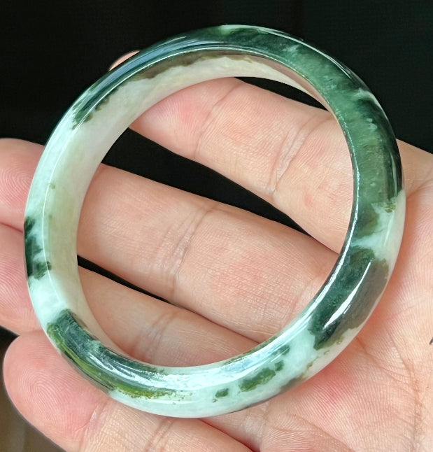 Close-up of fine crystalline texture and lush forest green patterns on icy milky white jadeite bangle