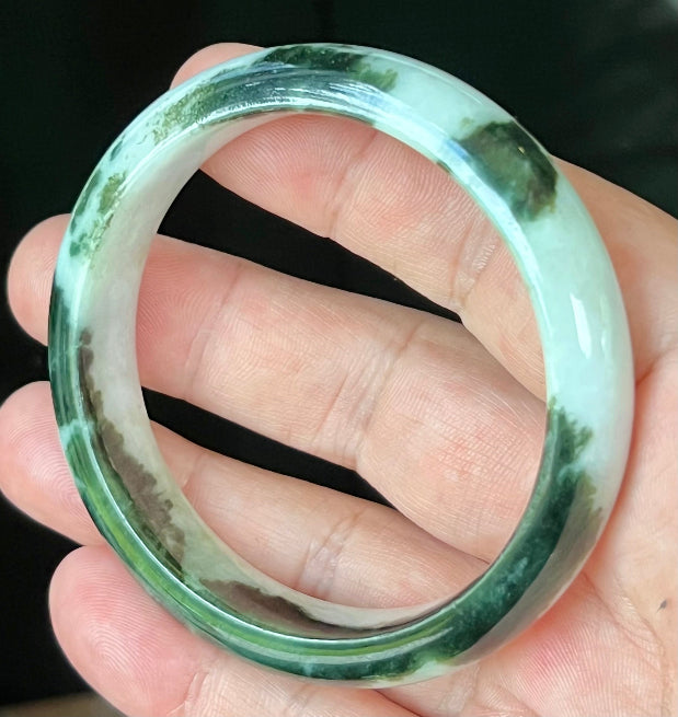 Close-up of fine crystalline texture and lush forest green patterns on icy milky white jadeite bangle