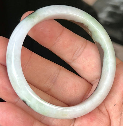Close-up of fine crystalline texture and lush forest green patterns on icy milky white jadeite bangle