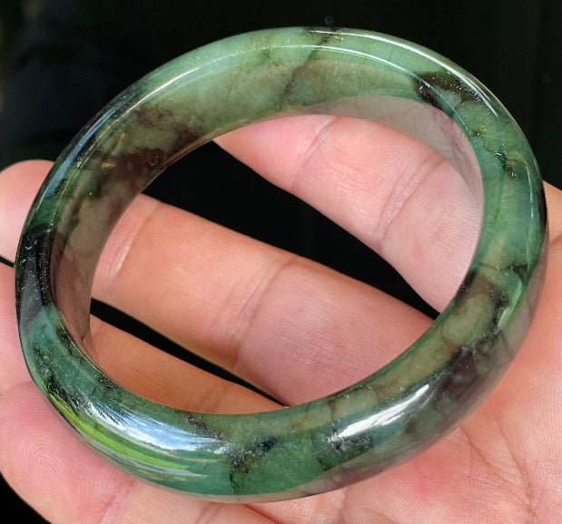 Close-up of fine crystalline texture and deep black tones on icy forest green jadeite bangle