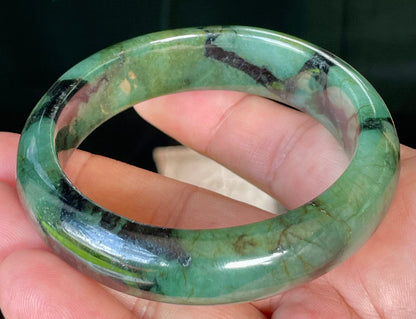 Close-up of fine crystalline texture and deep black tones on icy forest green jadeite bangle